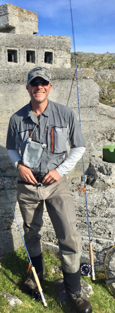 James Marcheselli, GFFUK South East instructor, in fly fishing gear with rods beside a stone ruin